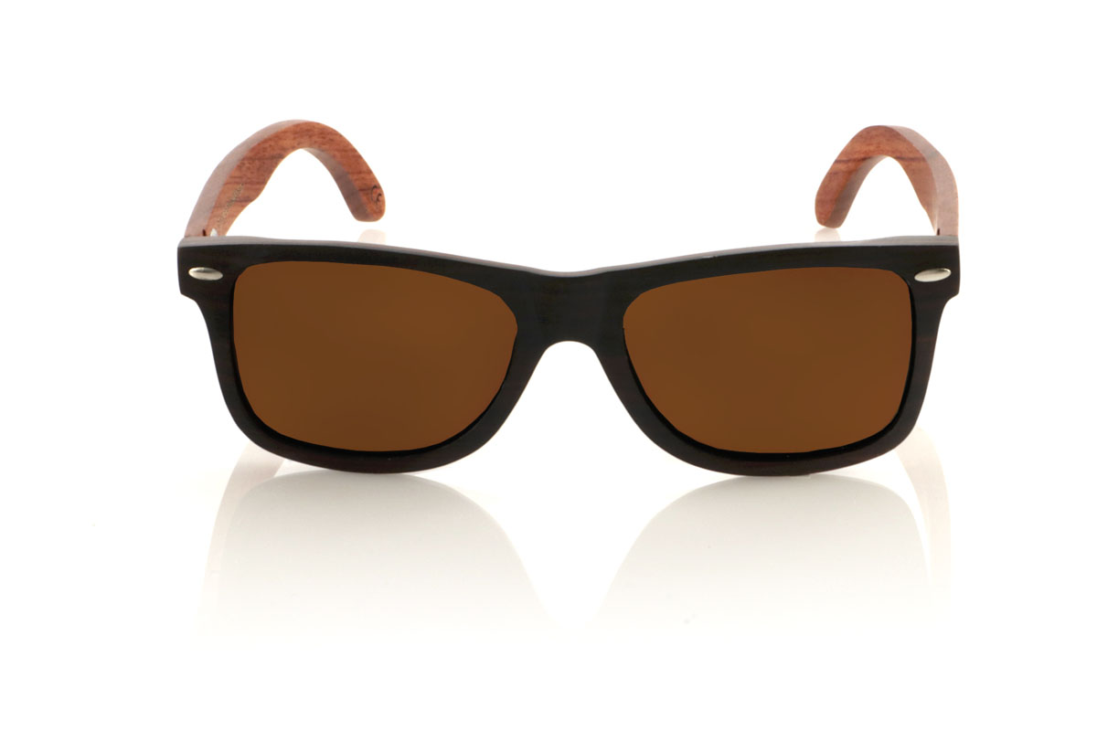 Wood eyewear of Ebony OSCAR. Gafas de sol de madera OSCAR, destaca su estilo inspirado en los clásicos, ofreciendo una silueta ancha que capta la atención. Estas gafas están meticulosamente fabricadas en capas de madera laminada, combinando ébano en el exterior y caoba en el centro, creando un efecto visual único y elegante, realzado por remaches plateados en el frontal. Las varillas de caoba prometen no solo estilo, sino también una durabilidad excepcional. Además de su diseño impecable, las OSCAR garantizan una visión clara y una protección total, asegurando que tus ojos estén protegidos con el máximo confort. Medidas: 149x45 mm. Calibre: 54. Con las OSCAR, experimentarás la perfecta unión entre moda y funcionalidad. for Wholesale & Retail | Root Sunglasses® 